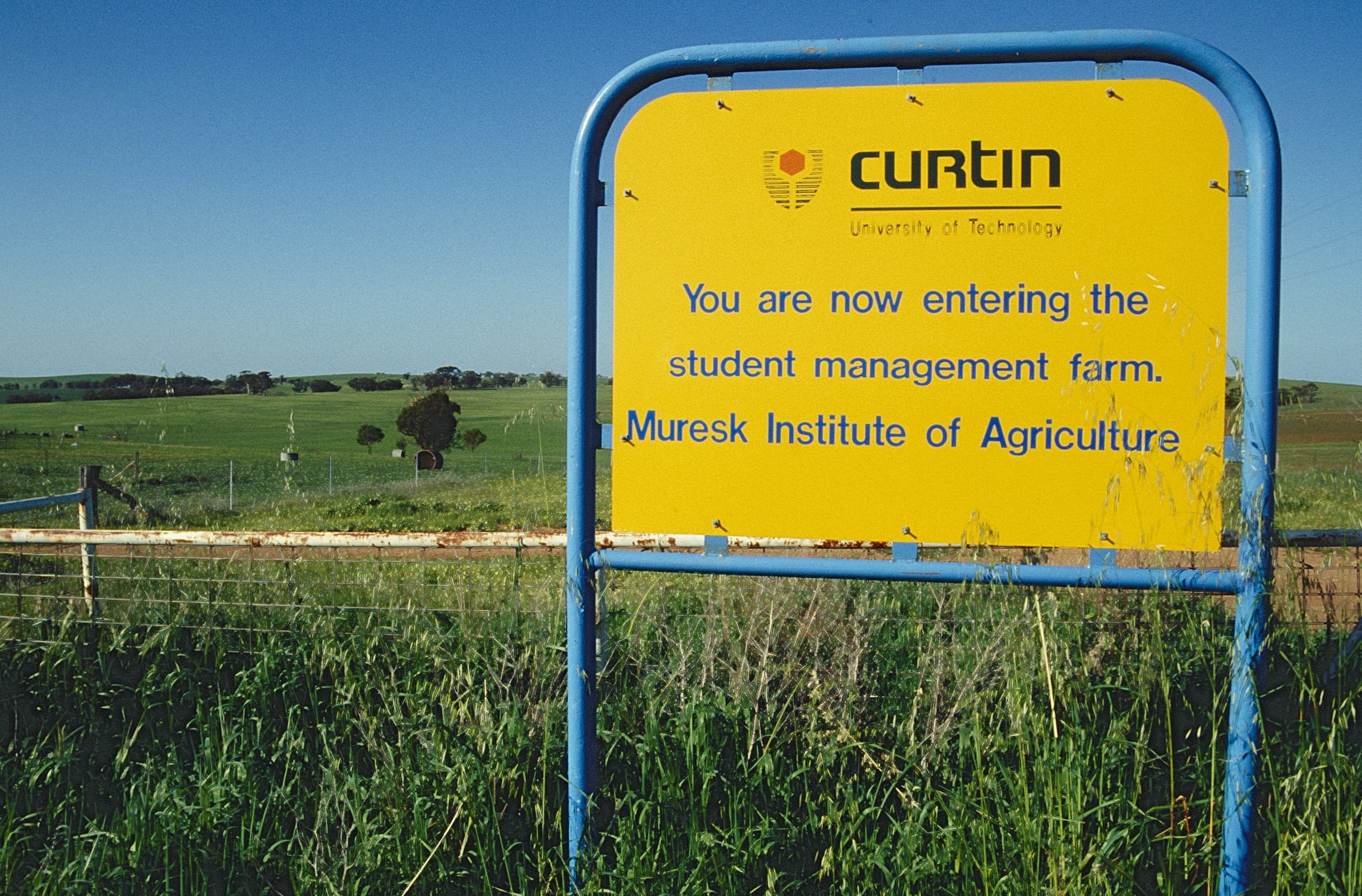 Yellow sign in front of a green field, it says "You are now entering the student management farm at the Muresk Institute of Agriculture."
