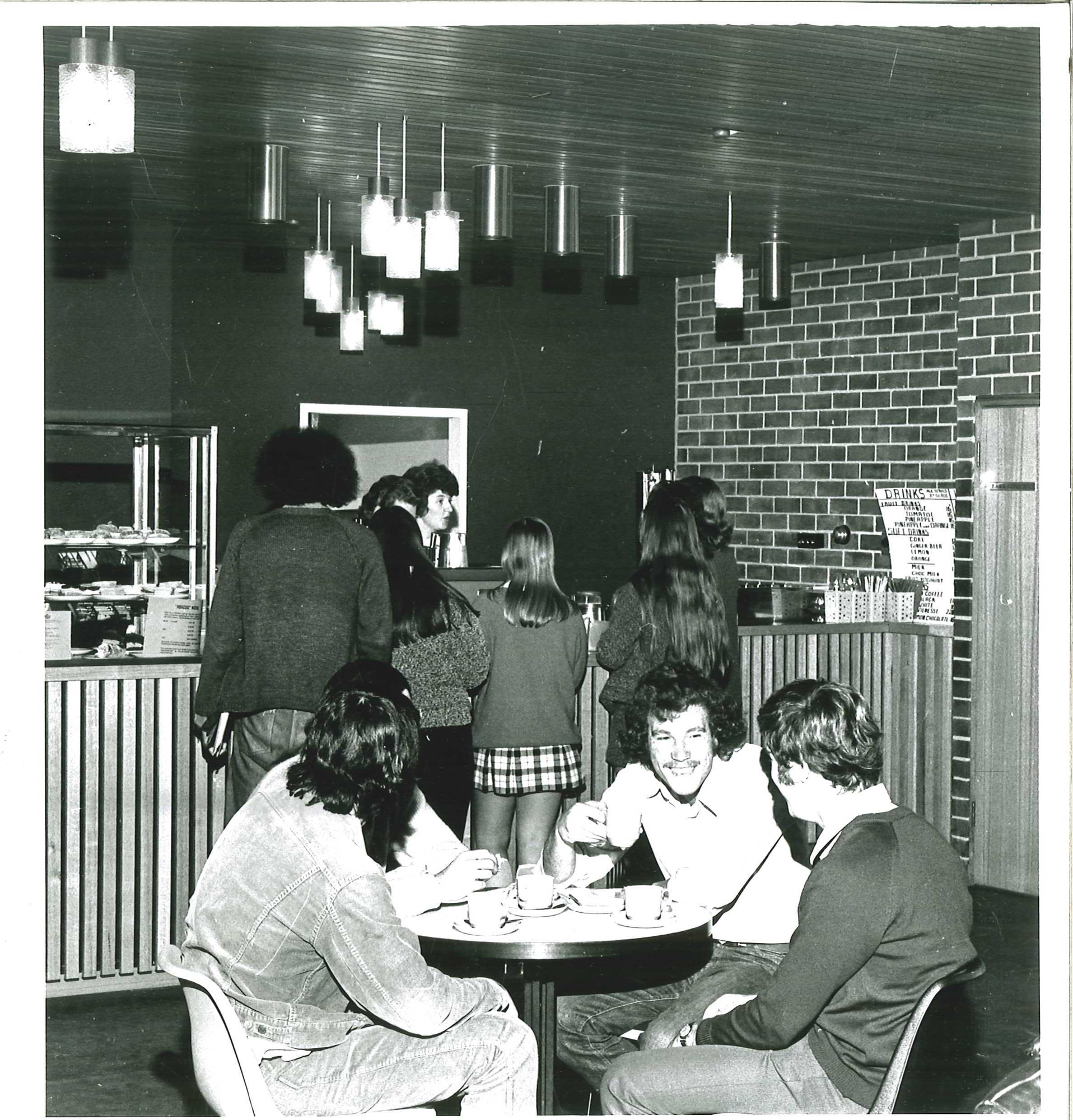 black and white photo of people sitting in a cafe