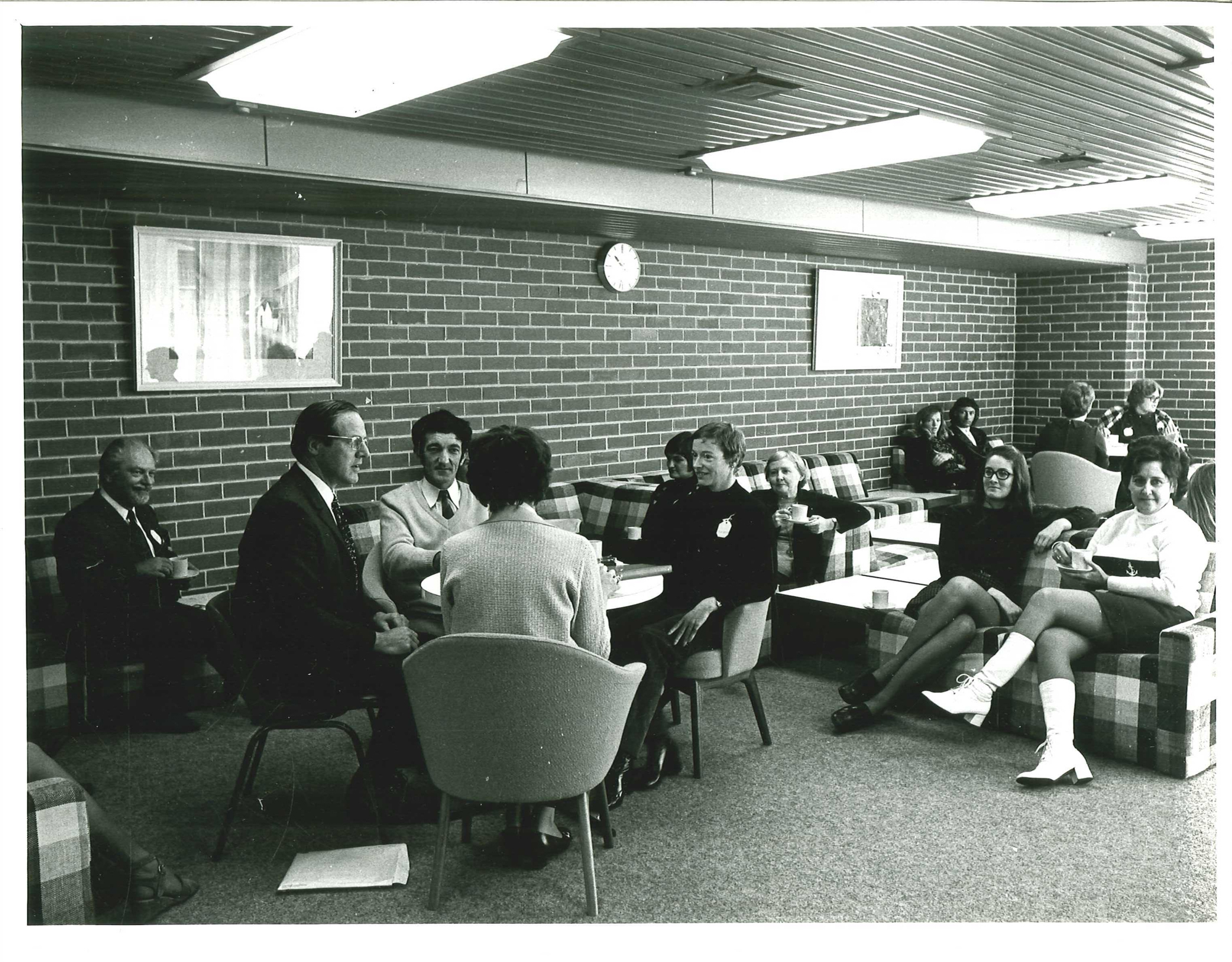 black and white photo of library staff sitting on chairs and couches in the staff room